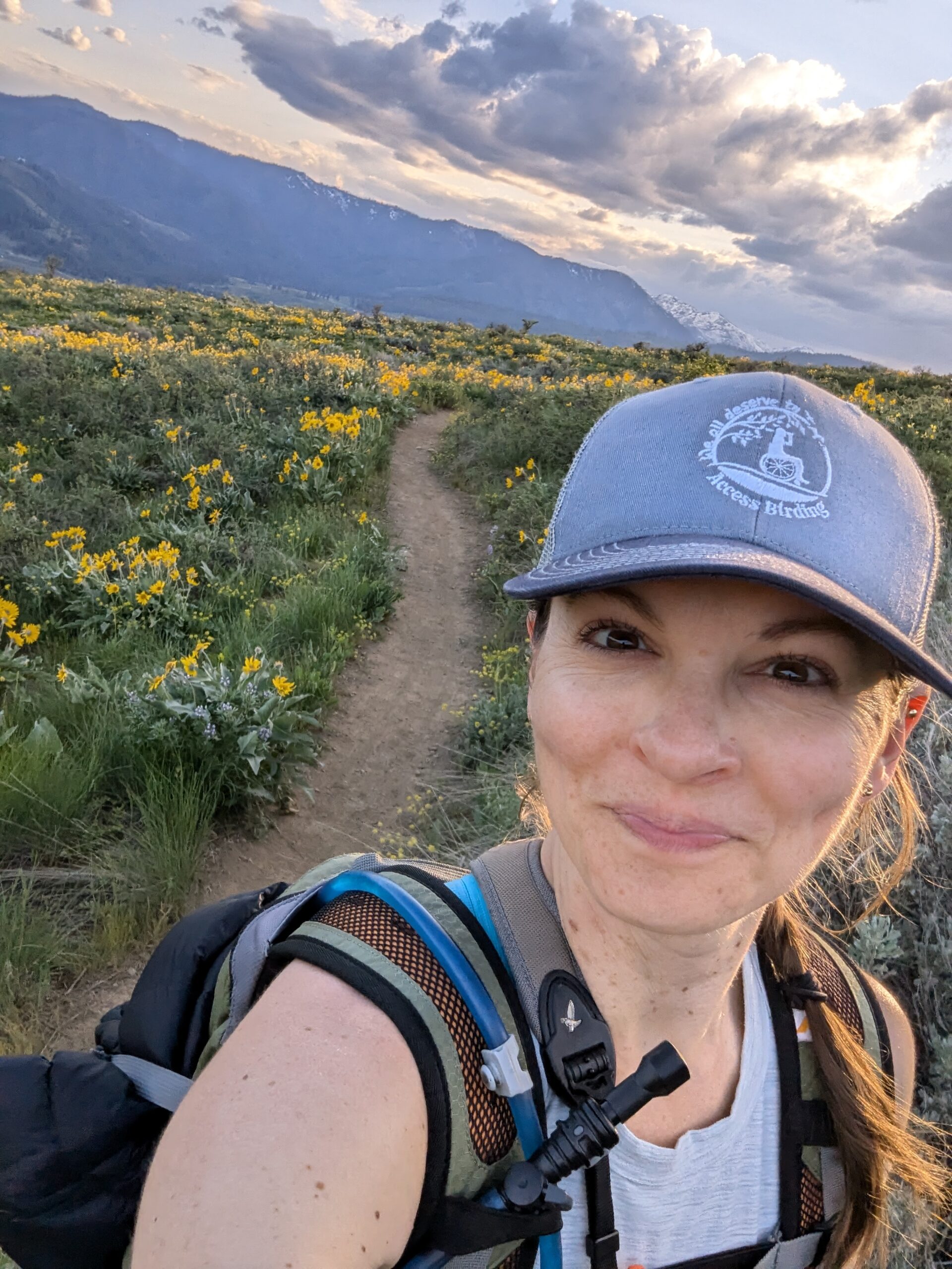 Woman takes selfie with sunset and balsamflowers in the background